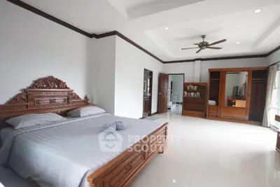 Spacious bedroom with elegant wooden furniture and ceiling fan in a bright, airy setting.
