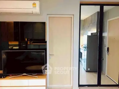 Modern apartment interior with sleek kitchen and stylish living area featuring TV and air conditioning.