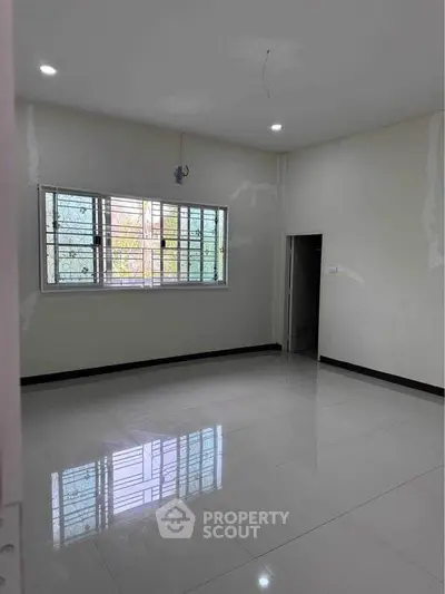 Spacious empty room with large window and glossy tiled floor