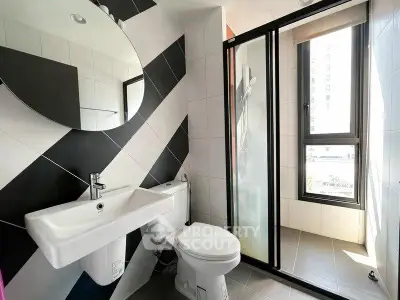 Modern bathroom with stylish black and white tiles, round mirror, and large window for natural light.