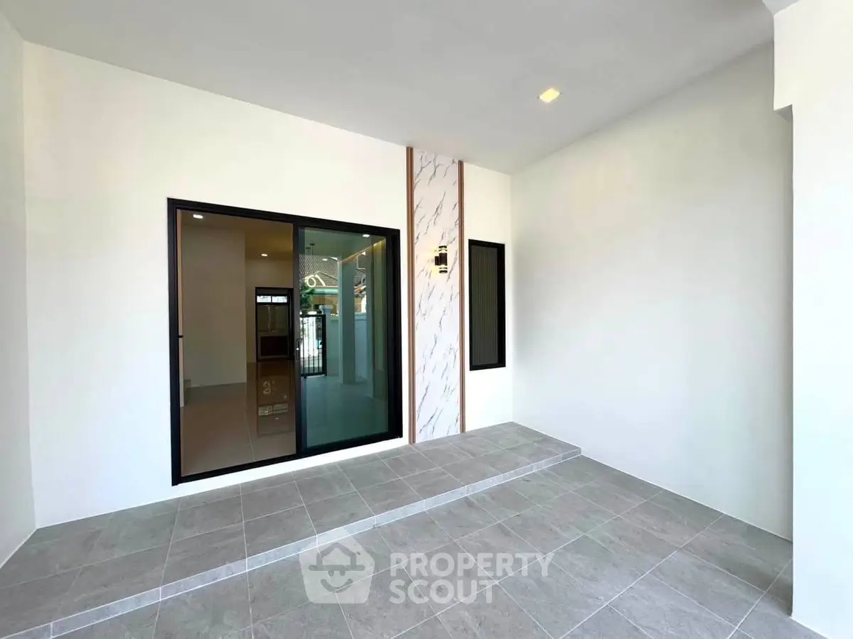 Modern minimalist entrance with large sliding glass door and tiled flooring
