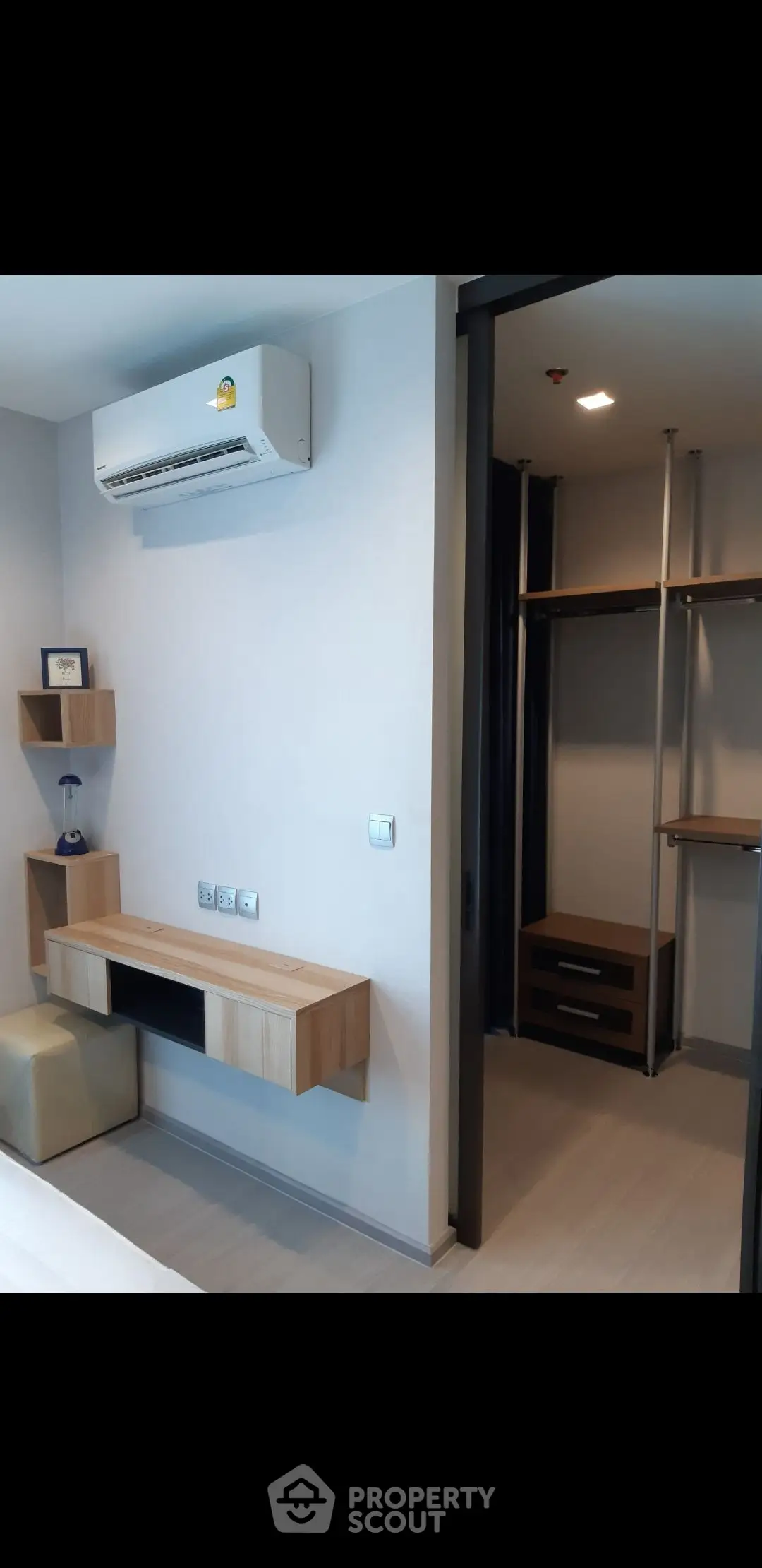 Modern bedroom with built-in desk and walk-in closet, featuring air conditioning and stylish shelving.