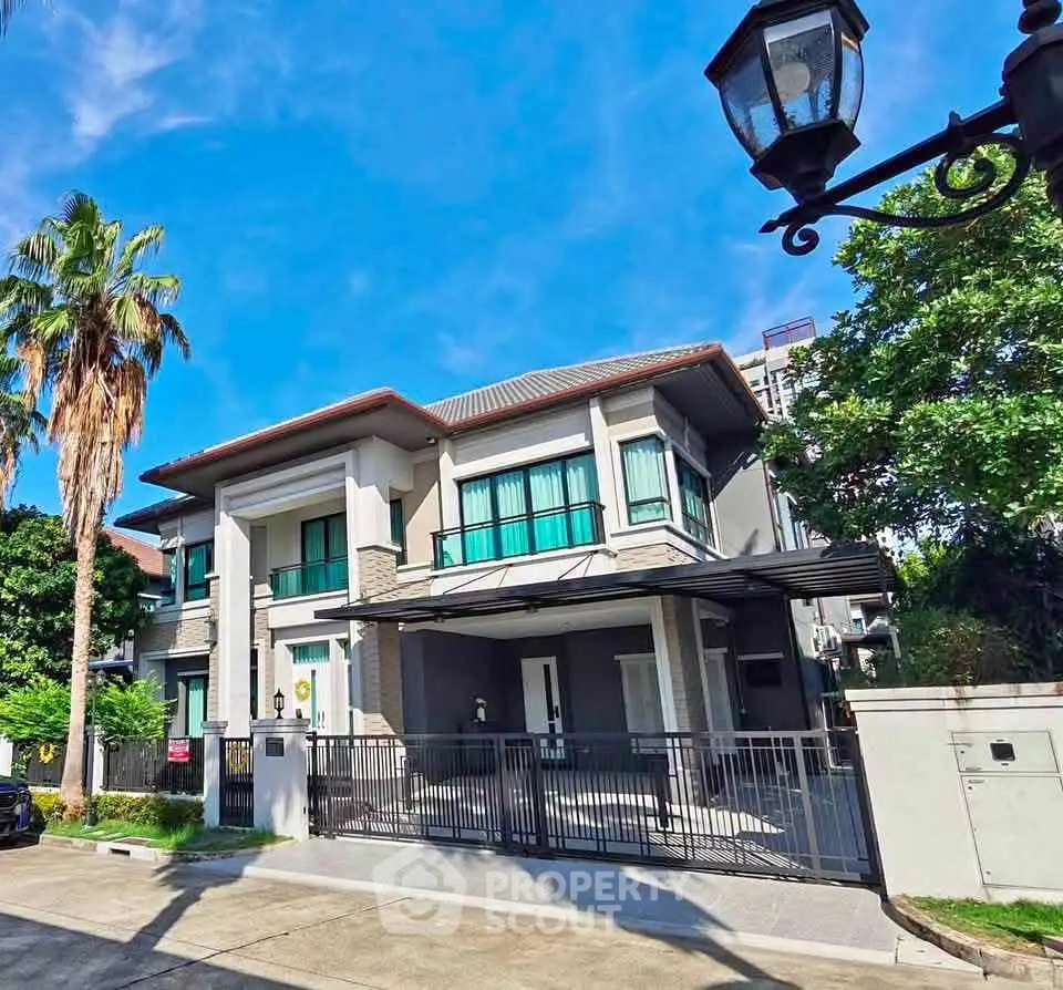 Stunning modern two-story house with gated entrance and lush greenery, perfect for luxurious living.