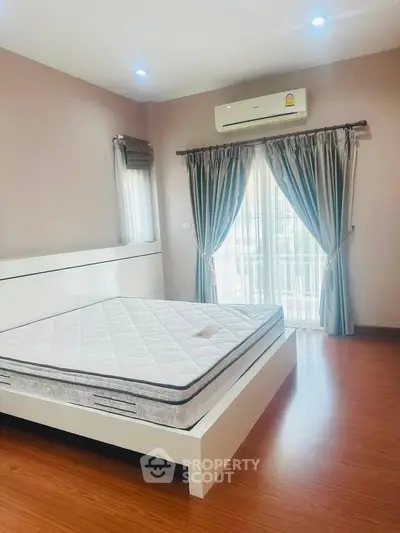 Spacious bedroom with modern design and natural light, featuring a comfortable bed and elegant curtains.