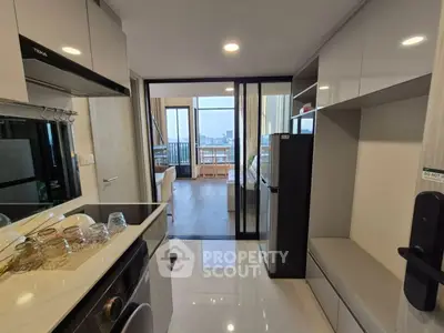 Modern kitchen with sleek cabinetry and open layout leading to a bright living area with city views.