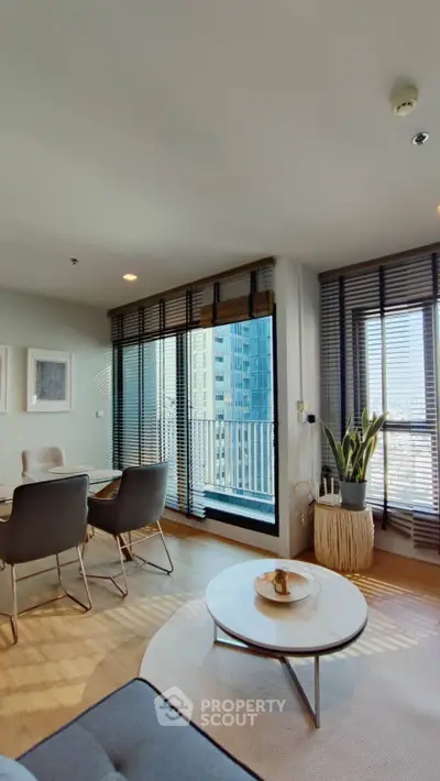 Modern living room with large windows and city view, featuring stylish furniture and decor.