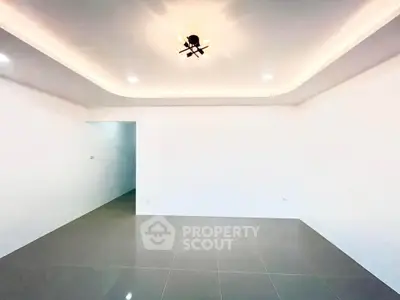 Spacious modern living room with sleek tile flooring and ambient ceiling lighting.