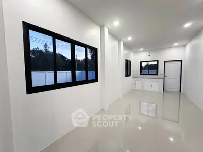Modern minimalist kitchen with sleek white cabinetry and large windows for natural light.
