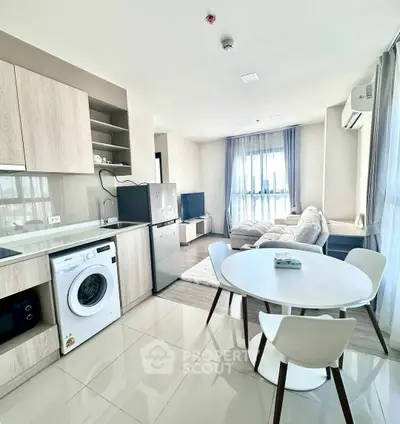 Modern open-plan living room and kitchen with sleek appliances and cozy seating area.