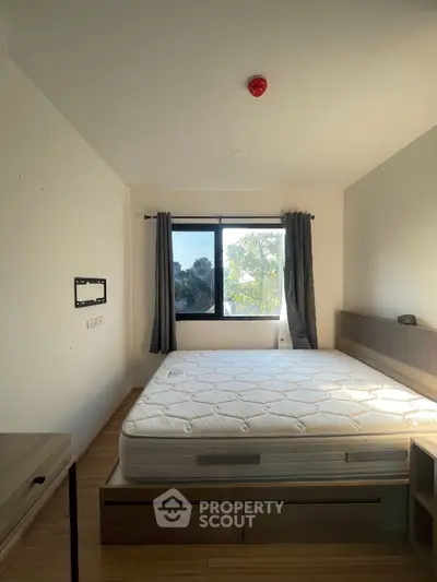 Spacious bedroom with large window and natural light, featuring a comfortable bed and modern furnishings.