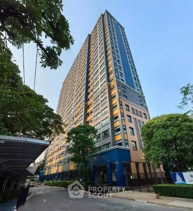 Modern high-rise residential building with lush greenery and clear blue sky.