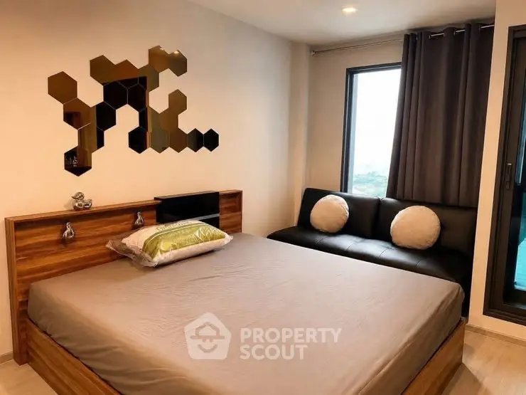 Modern bedroom with stylish decor and large window offering natural light.