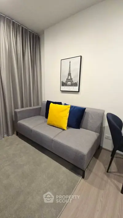 Modern living room with stylish gray sofa and vibrant yellow cushion, elegant decor and cozy ambiance.