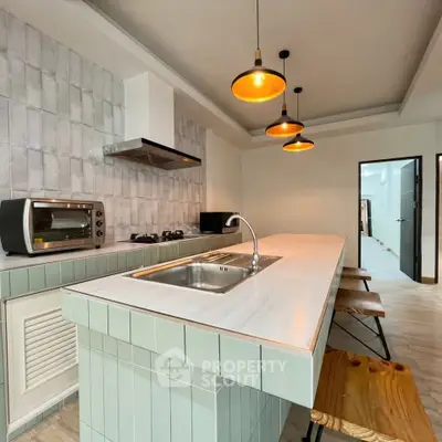 Modern kitchen with island, pendant lights, and gas stove in stylish apartment.