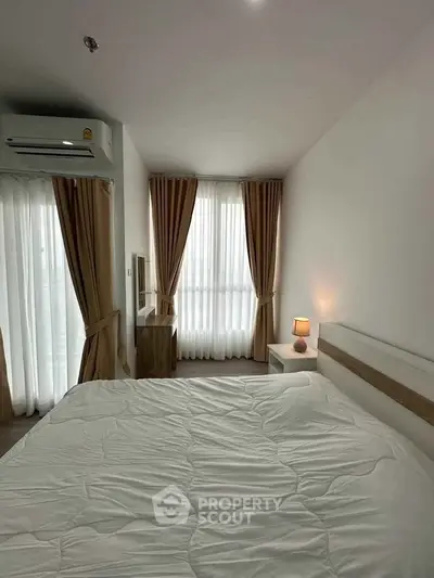 Cozy bedroom with natural light, modern furnishings, and elegant curtains in a stylish apartment.