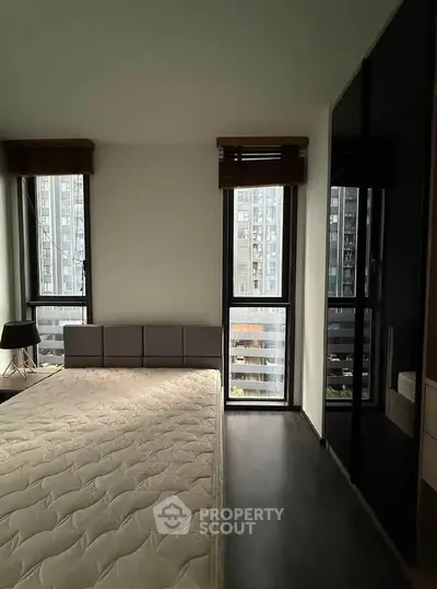 Modern bedroom with large windows and city view, featuring sleek design and ample natural light.