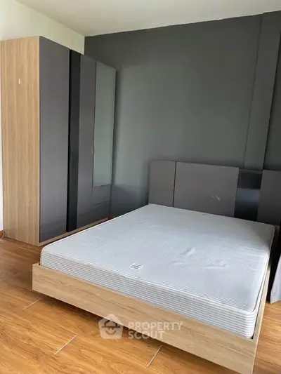 Modern bedroom with sleek wardrobe and minimalist bed frame on wooden flooring.