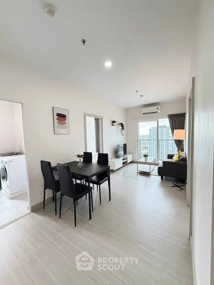 Modern living room with dining area and city view, featuring sleek furniture and bright natural light.