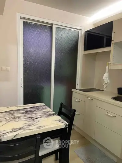 Modern kitchen with marble table and sleek cabinetry in a compact layout.