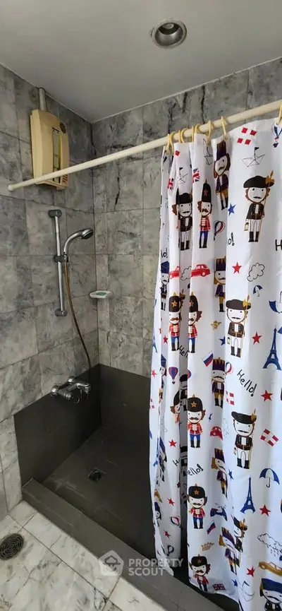 Charming bathroom with playful shower curtain and modern fixtures in a stylish marble setting.