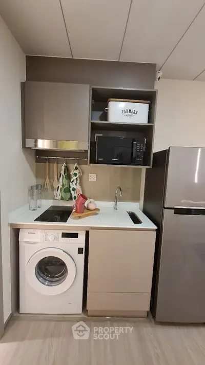 Compact kitchen with modern appliances including washing machine and fridge