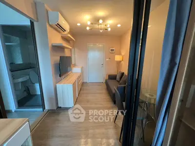 Modern living room with sleek furniture and ambient lighting, adjacent to a compact bathroom.