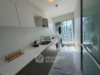 Modern kitchen with sleek cabinetry and laundry appliances in a bright, sunlit space.