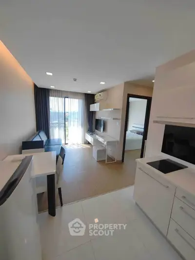 Modern open-plan living room with sleek kitchen and balcony view, perfect for urban living.