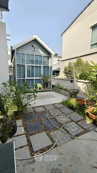 Charming garden view of modern house with lush greenery and stylish paving stones.
