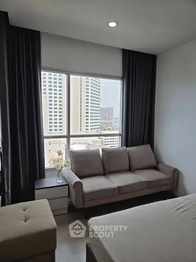 Modern bedroom with city view and cozy sofa near window