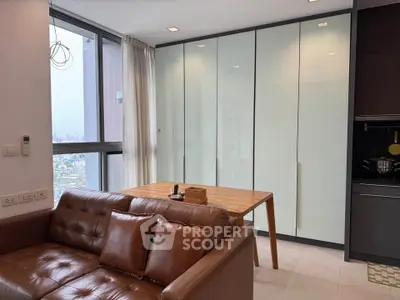 Modern living room with leather sofa and dining area, city view through large window.