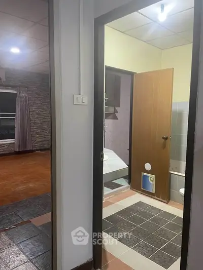 Cozy interior view featuring a bathroom and adjacent room with tiled flooring, ideal for renovation.