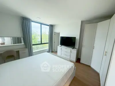 Spacious bedroom with large window and modern furnishings