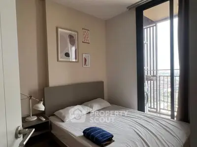 Cozy bedroom with modern decor and balcony view, perfect for urban living.