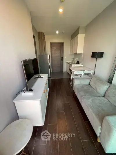 Modern living room with sleek furniture and open kitchen layout in a stylish apartment.