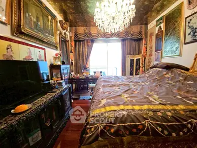 Luxurious bedroom with chandelier and ornate decor, featuring a large bed and elegant drapery.