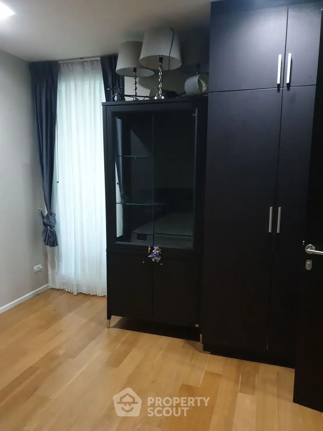 Spacious room with elegant wooden flooring and modern dark wood furniture.