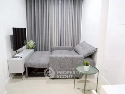 Modern living room with stylish gray sofa and sleek TV setup.