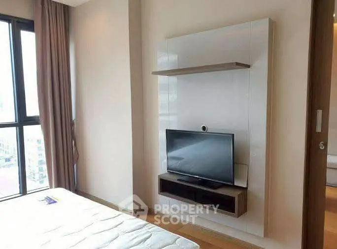 Modern bedroom with mounted TV and large window offering city views.