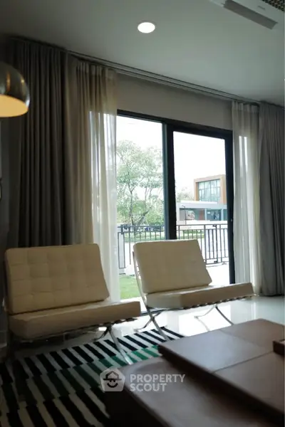 Modern living room with stylish chairs and large window overlooking garden