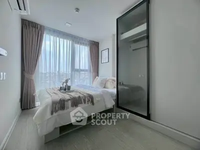 Modern bedroom with large window and mirrored wardrobe in a stylish apartment.