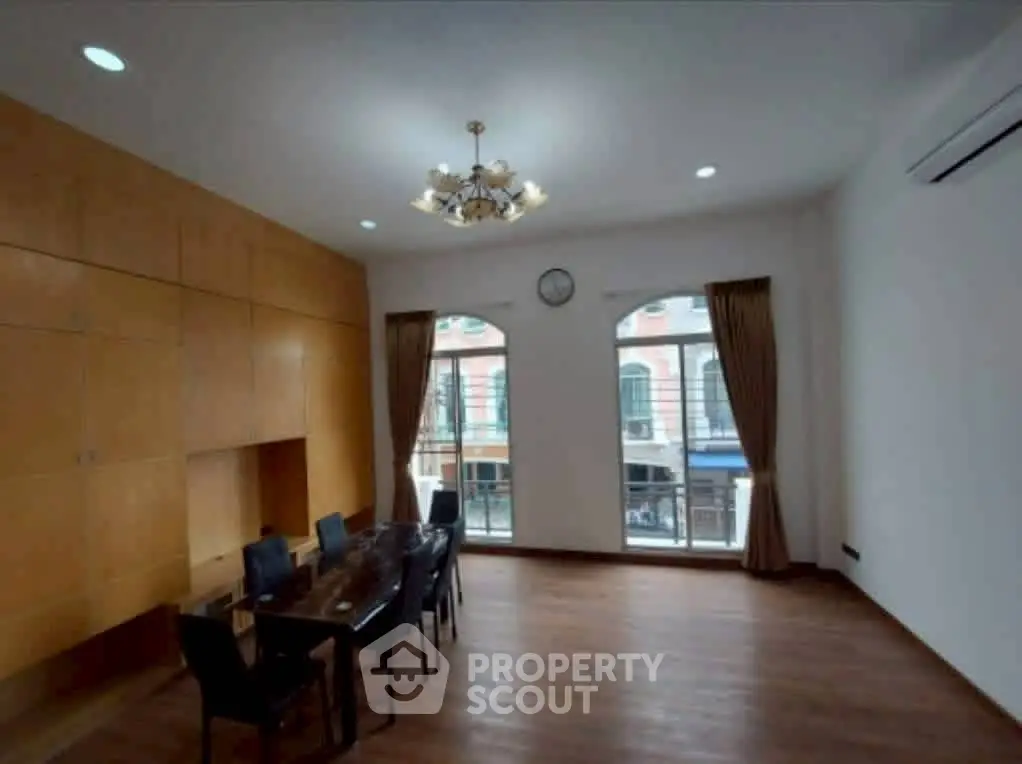Spacious dining area with elegant chandelier and large windows offering city views.