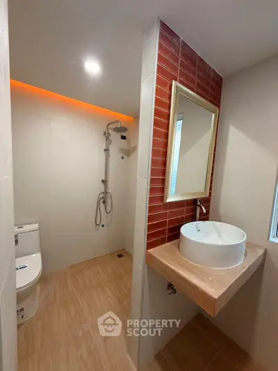 Modern bathroom with sleek fixtures and stylish red accent wall.