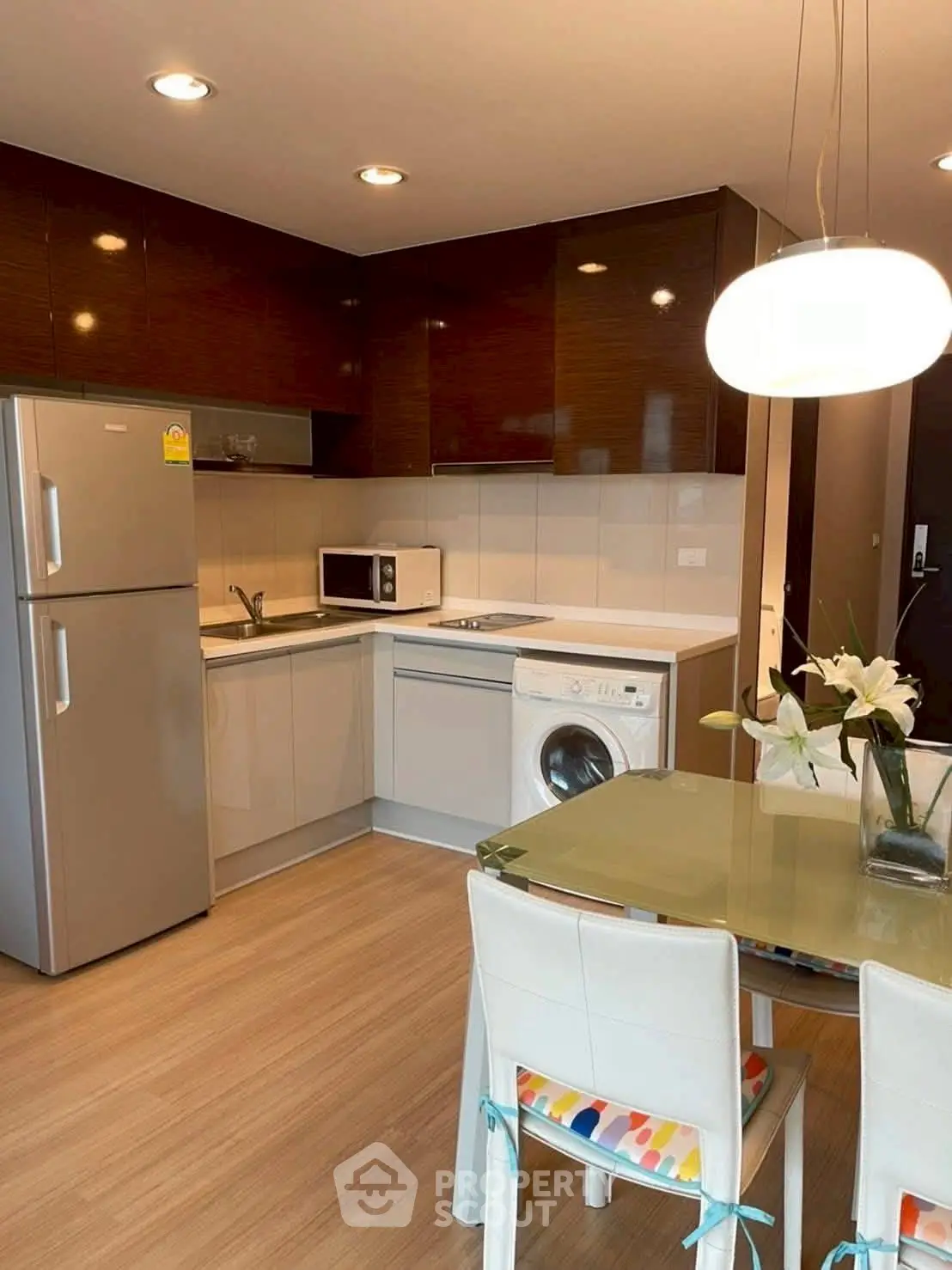 Modern kitchen with sleek appliances and dining area, featuring washing machine and microwave.