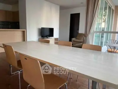 Spacious dining area with modern wooden table and chairs, adjacent to cozy living space with natural light.