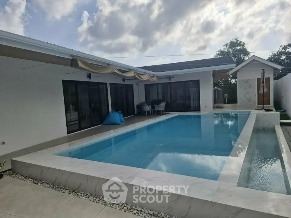 Luxurious modern home with stunning pool and outdoor seating area, perfect for relaxation and entertainment.