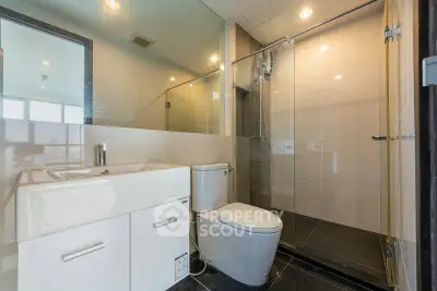 Modern bathroom with sleek fixtures and glass shower enclosure in a contemporary apartment.