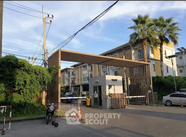 Modern residential entrance with security gate and lush greenery