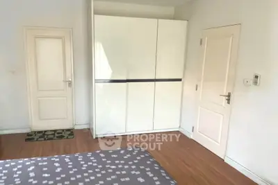 Spacious bedroom with modern wardrobe and wooden flooring