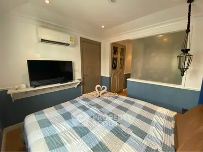 Cozy bedroom with modern decor and air conditioning, featuring a stylish bedspread and elegant lighting.